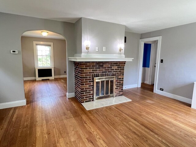 65 Franklin Rd, Longmeadow, MA 01106 - unfurnished living room with arched walkways, a fireplace, and wood finished floors