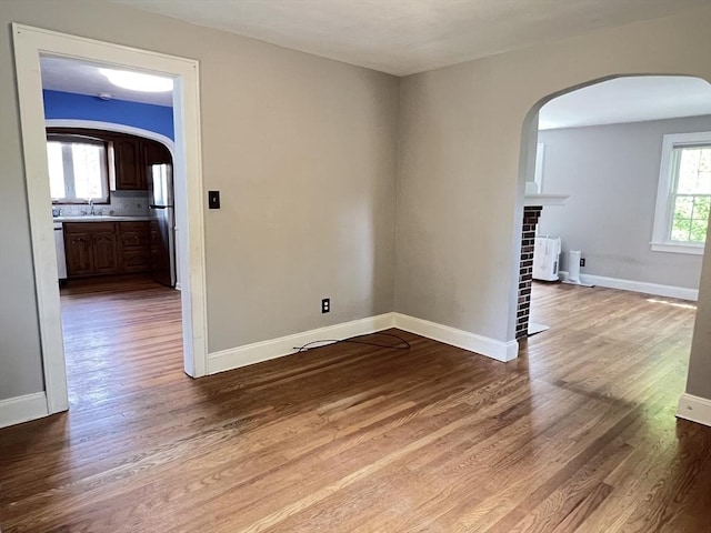 65 Franklin Rd, Longmeadow, MA 01106 - unfurnished room featuring arched walkways, wood finished floors, radiator heating unit, and a fireplace