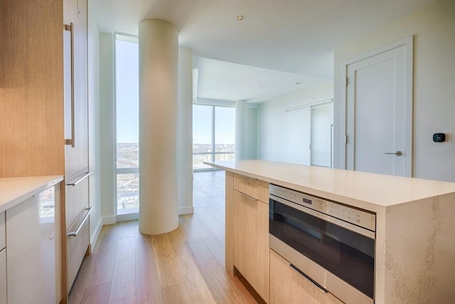 188 Brookline Ave Unit 23C, Boston, MA 02215 - kitchen with modern cabinets, light wood finished floors, wall oven, light brown cabinetry, and a wall of windows