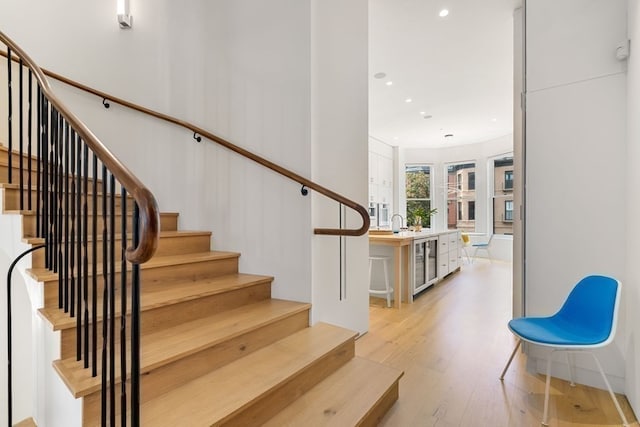 staircase with beverage cooler and hardwood / wood-style flooring