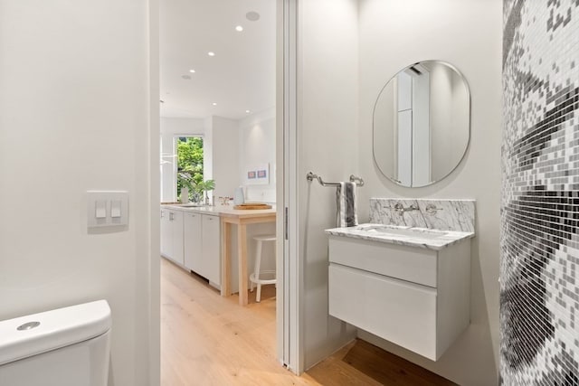 bathroom with vanity, toilet, wood-type flooring, and decorative backsplash