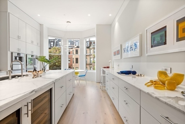 interior space with light wood-type flooring, a wealth of natural light, white cabinets, and beverage cooler