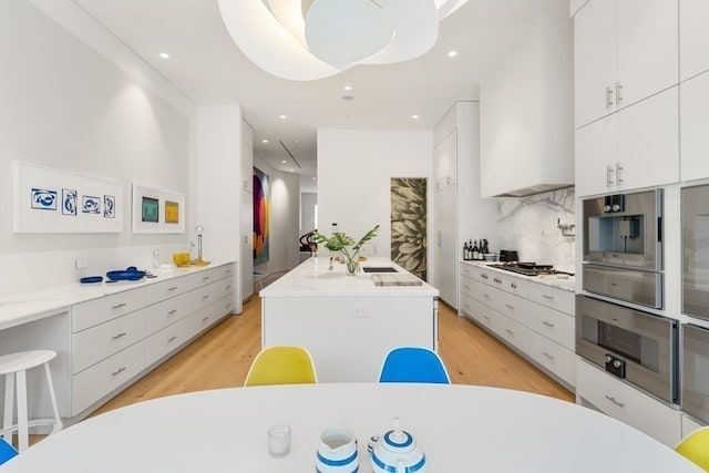 kitchen featuring backsplash, white cabinetry, and light hardwood / wood-style floors