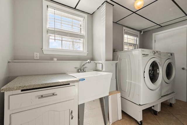 clothes washing area featuring plenty of natural light, washing machine and dryer, and light tile patterned floors