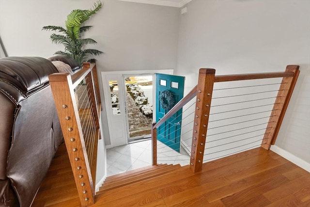 stairs with hardwood / wood-style floors and crown molding