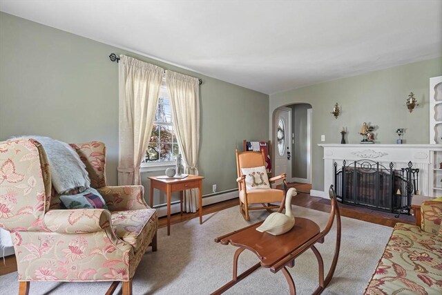 77 Center St, Ashburnham, MA 01430 - living area with arched walkways, a fireplace with flush hearth, wood finished floors, and baseboard heating