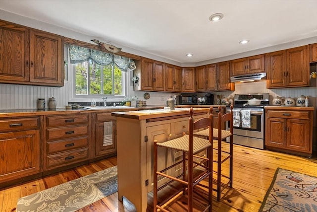 77 Center St, Ashburnham, MA 01430 - kitchen featuring stainless steel range, under cabinet range hood, a sink, a kitchen island, and light wood-type flooring