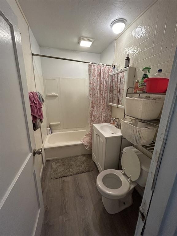 full bathroom featuring vanity, a textured ceiling, shower / bathtub combination with curtain, hardwood / wood-style floors, and toilet