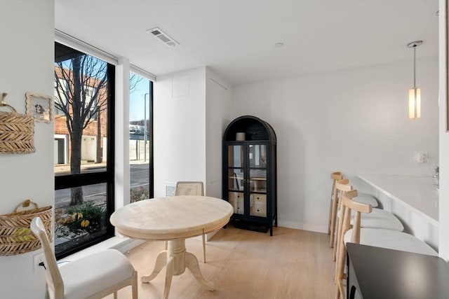 dining room with floor to ceiling windows, visible vents, and light wood-style floors