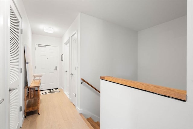 corridor with light wood-style floors and an upstairs landing