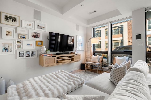 living room with baseboards, a tray ceiling, visible vents, and wood finished floors