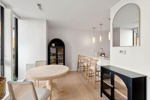 dining area with light wood finished floors and visible vents