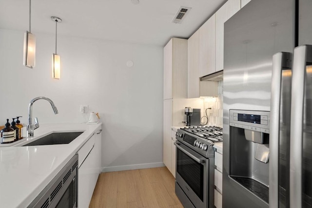 kitchen featuring light countertops, appliances with stainless steel finishes, a sink, and visible vents