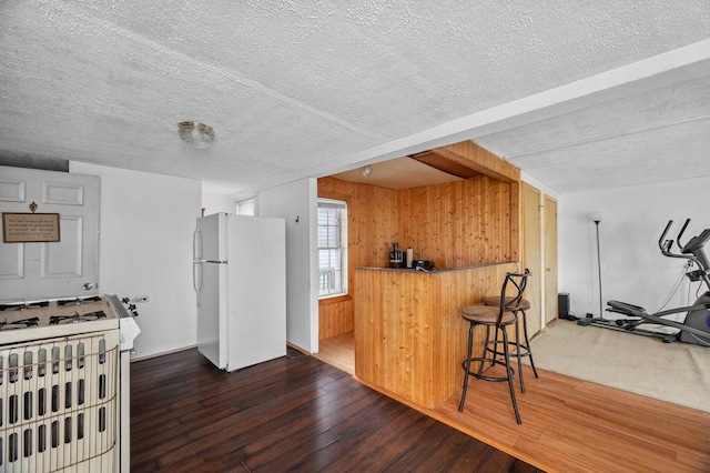 17-19 Whitehall Rd, Amesbury, MA 01913 - kitchen featuring white appliances, wooden walls, hardwood / wood-style floors, a textured ceiling, and a kitchen breakfast bar