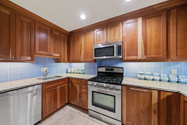 kitchen with sink, light stone countertops, stainless steel appliances, and backsplash