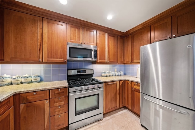 kitchen featuring stainless steel appliances, light stone countertops, light tile patterned flooring, and decorative backsplash