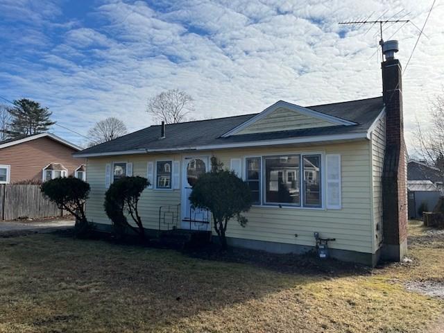 view of front of house with a chimney, fence, and a front yard