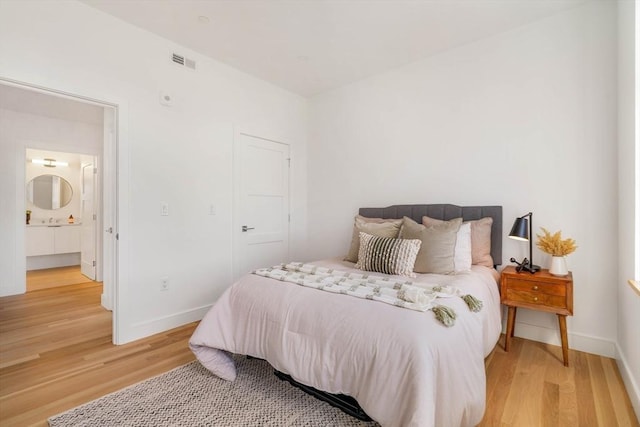 bedroom featuring wood-type flooring and ensuite bath