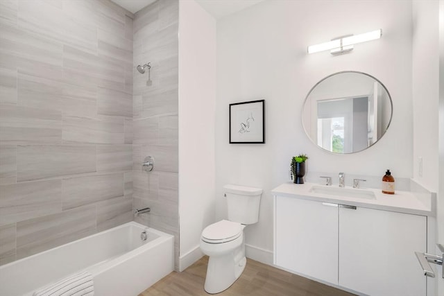 full bathroom with hardwood / wood-style flooring, tiled shower / bath combo, vanity, and toilet