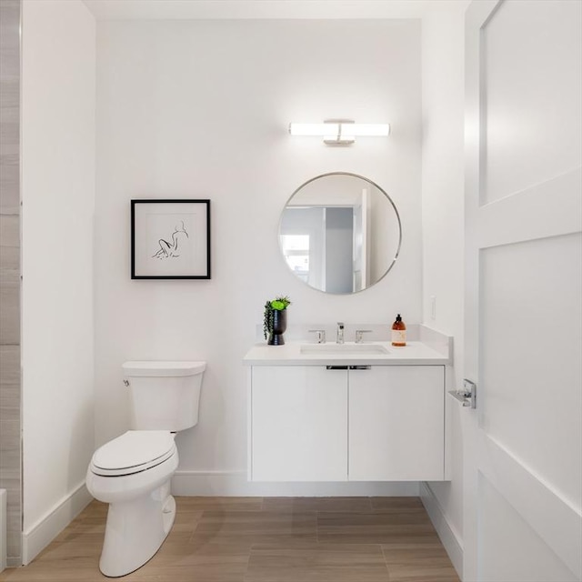 bathroom with wood-type flooring, toilet, and vanity