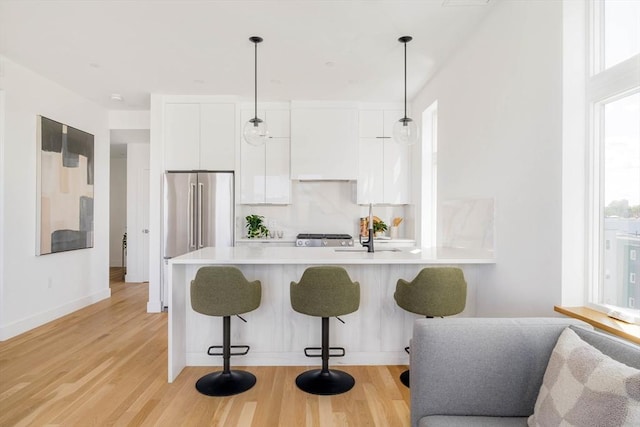 kitchen with plenty of natural light, white cabinetry, light hardwood / wood-style flooring, and pendant lighting