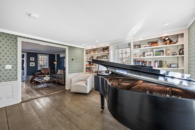 sitting room featuring built in shelves, ornamental molding, wainscoting, wood-type flooring, and wallpapered walls