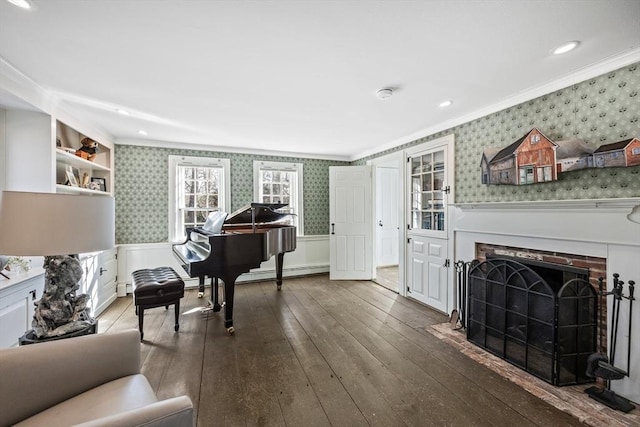 living area featuring wallpapered walls, wainscoting, dark wood-style flooring, crown molding, and a fireplace