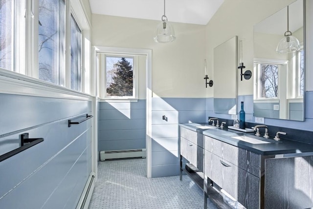 full bath featuring a wainscoted wall, double vanity, baseboard heating, and a sink