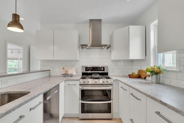 215 Norfolk St Unit 2, Cambridge, MA 02139 - kitchen with wall chimney exhaust hood, appliances with stainless steel finishes, light stone counters, white cabinetry, and tasteful backsplash
