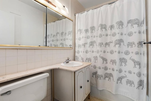 full bathroom featuring tile walls, decorative backsplash, vanity, toilet, and shower / bath combo with shower curtain