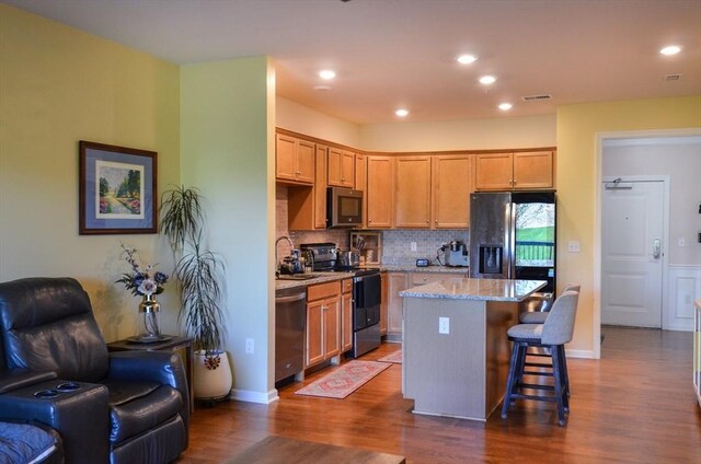 kitchen featuring a kitchen breakfast bar, dark wood finished floors, a center island, stainless steel appliances, and open floor plan