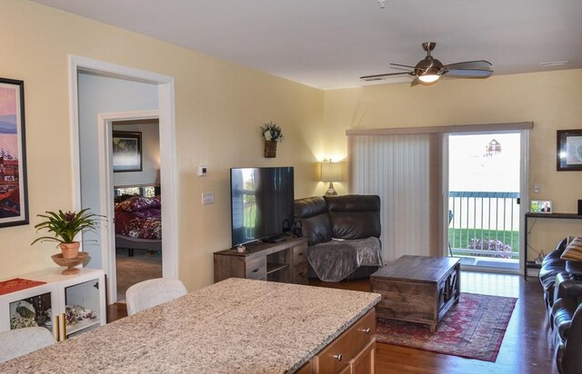 living room featuring a ceiling fan and dark wood-type flooring