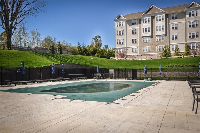 pool featuring a lawn, a patio, and fence