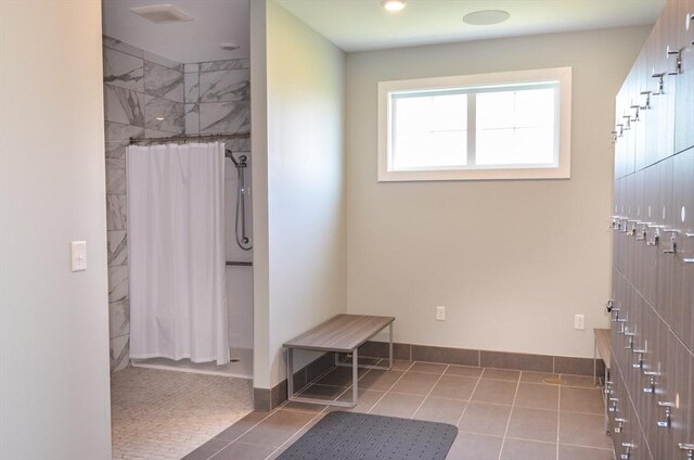 bathroom featuring tile patterned flooring, baseboards, and a tile shower