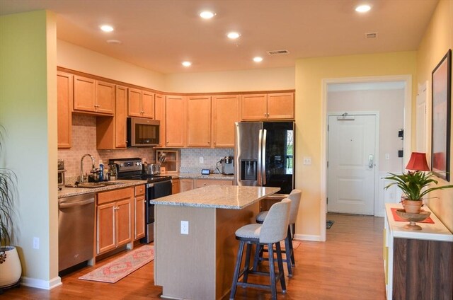 kitchen with visible vents, decorative backsplash, a sink, light wood-style flooring, and stainless steel appliances
