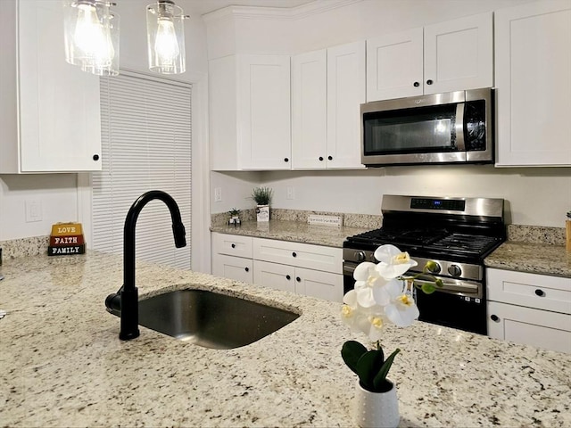 kitchen with appliances with stainless steel finishes, white cabinets, and a sink