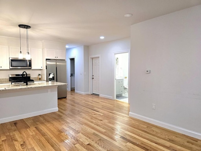 kitchen with light wood finished floors, baseboards, white cabinets, appliances with stainless steel finishes, and a sink