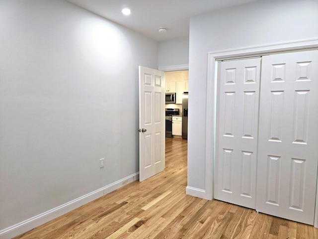 corridor featuring light wood-style flooring and baseboards