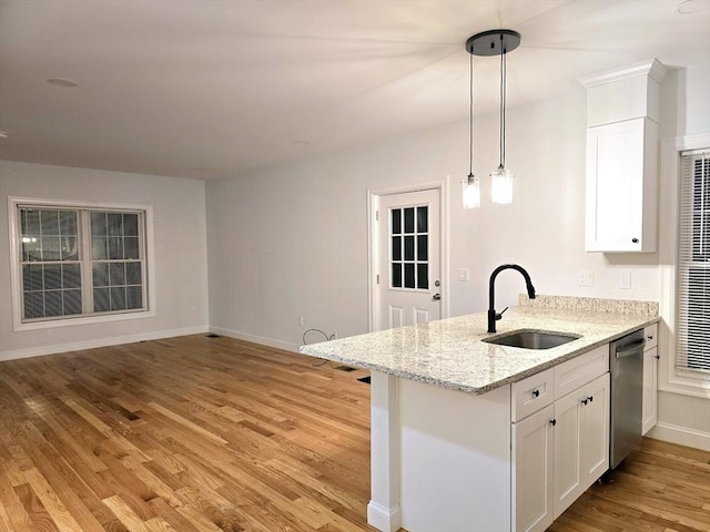 kitchen featuring dishwasher, a peninsula, light wood-style floors, white cabinetry, and a sink