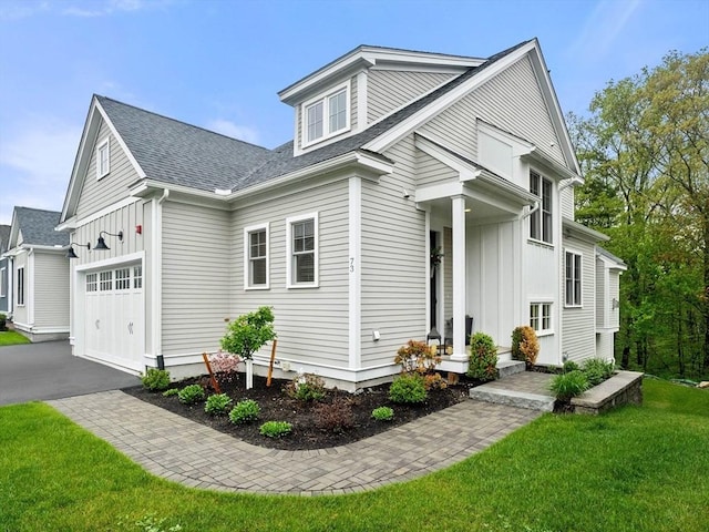 view of front of house featuring board and batten siding, a front lawn, asphalt driveway, and a shingled roof