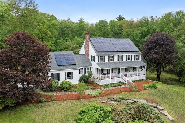 176 Spring St, Hopkinton, MA 01748 - back of house featuring a porch, roof mounted solar panels, a yard, and a view of trees