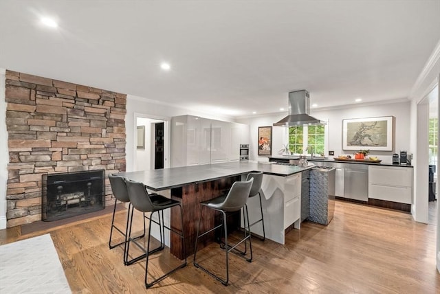 176 Spring St, Hopkinton, MA 01748 - kitchen featuring dark countertops, island range hood, ornamental molding, appliances with stainless steel finishes, and a kitchen island