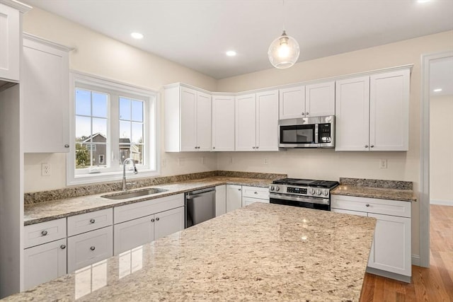 66-3 Parish Rd, Georgetown, MA 01833 - kitchen featuring appliances with stainless steel finishes, a sink, wood finished floors, light stone counters, and white cabinetry