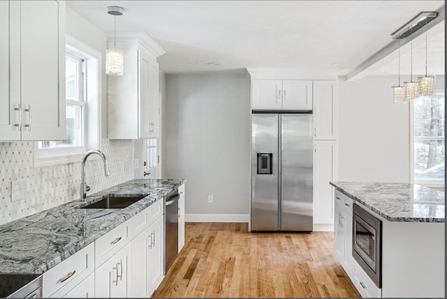 kitchen featuring decorative light fixtures, sink, white cabinets, decorative backsplash, and stainless steel appliances