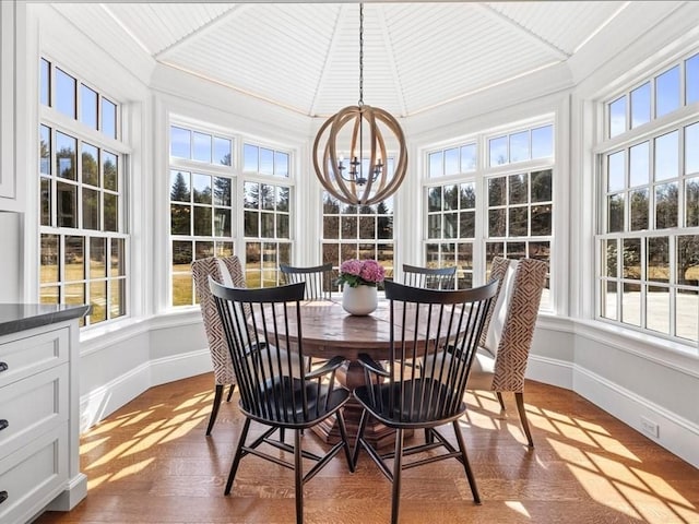 sunroom featuring a healthy amount of sunlight, an inviting chandelier, and lofted ceiling