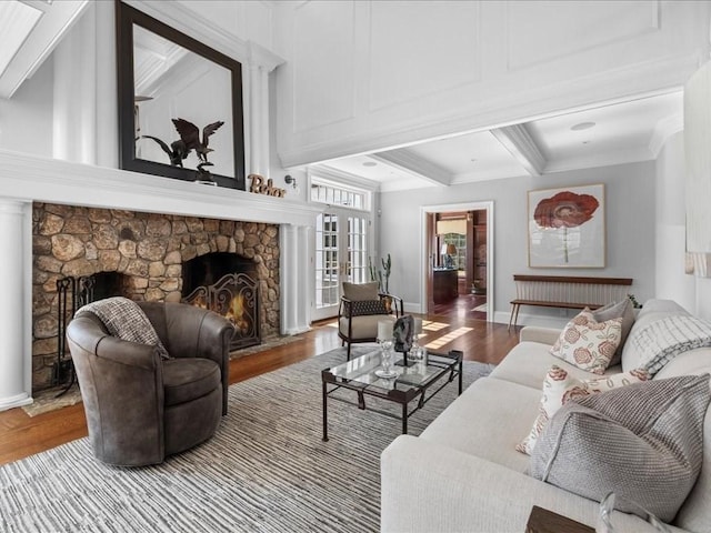 living area with a fireplace, ornamental molding, wood finished floors, beamed ceiling, and baseboards