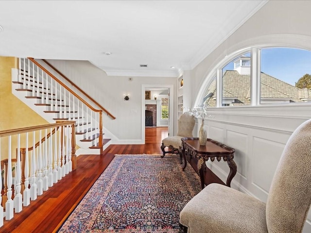 foyer with a decorative wall, wood finished floors, visible vents, ornamental molding, and stairway