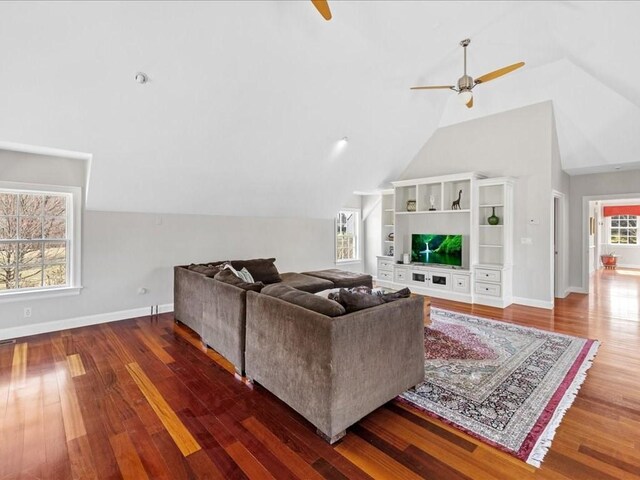 living room with ceiling fan, vaulted ceiling, baseboards, and wood finished floors