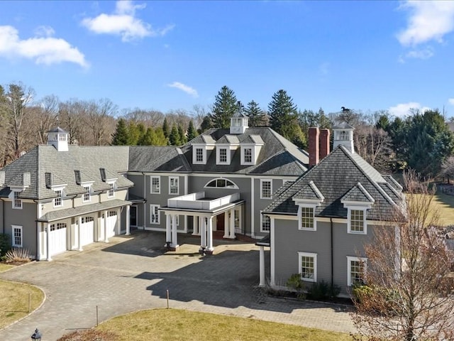 view of front of home featuring driveway, an attached garage, and a chimney