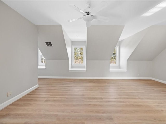 additional living space with a ceiling fan, wood finished floors, visible vents, and baseboards